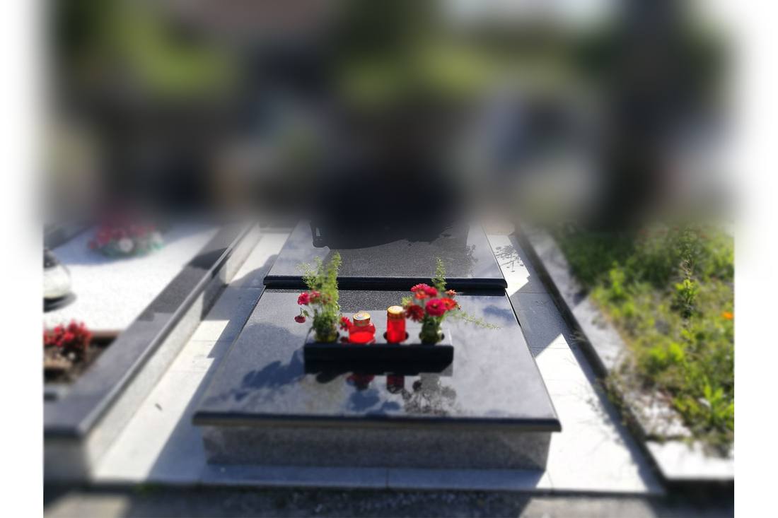 Spomenik od crnog poliranog granita: pokrovna ploča s odsjajem, obrađeni rubovi i uska tamna traka po sredini.